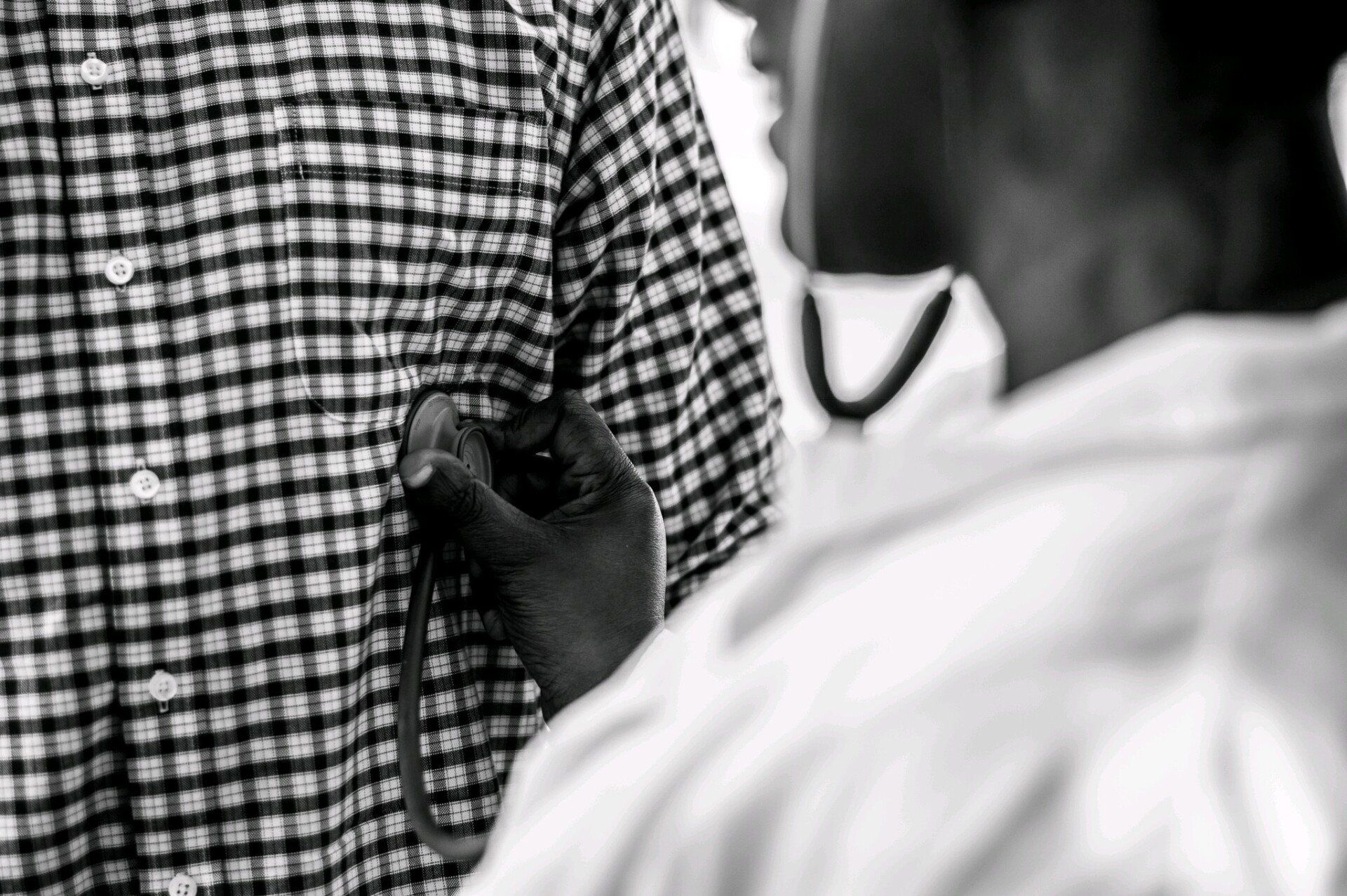 woman listening to heart beat with a stethescope of a person with a plaid shirt on