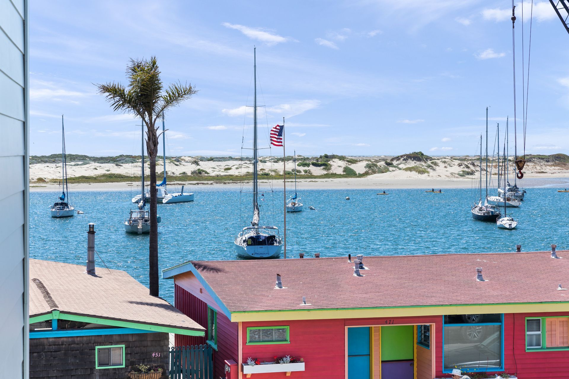 A pink house is sitting next to a body of water with boats in it.