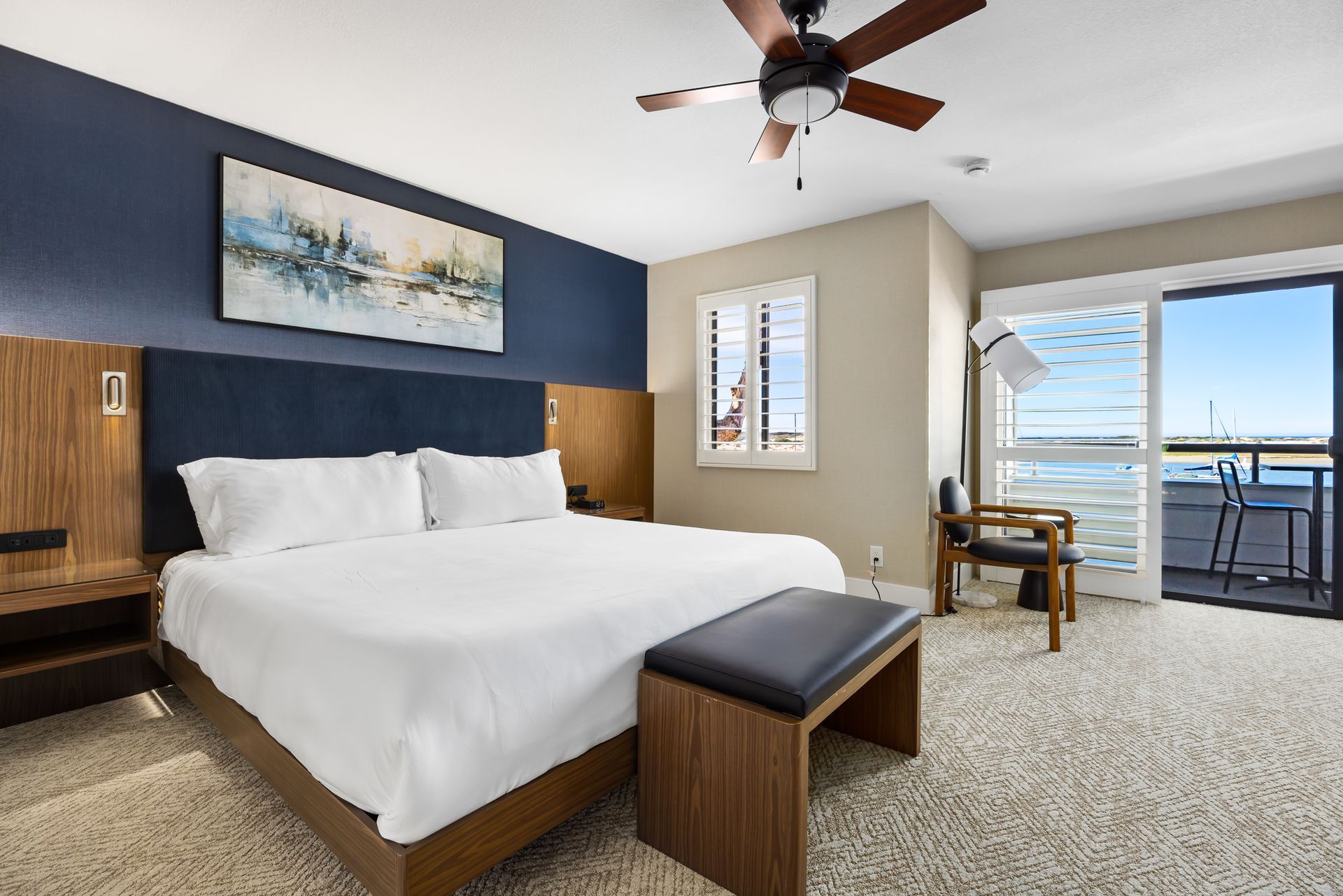 A hotel room with a king size bed , dresser , chair and television.