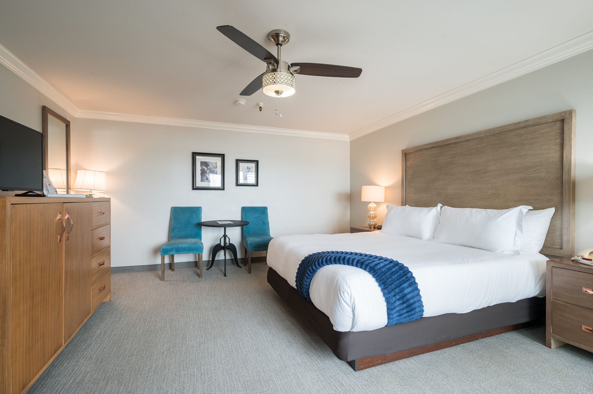 A hotel room with a king size bed and a ceiling fan.