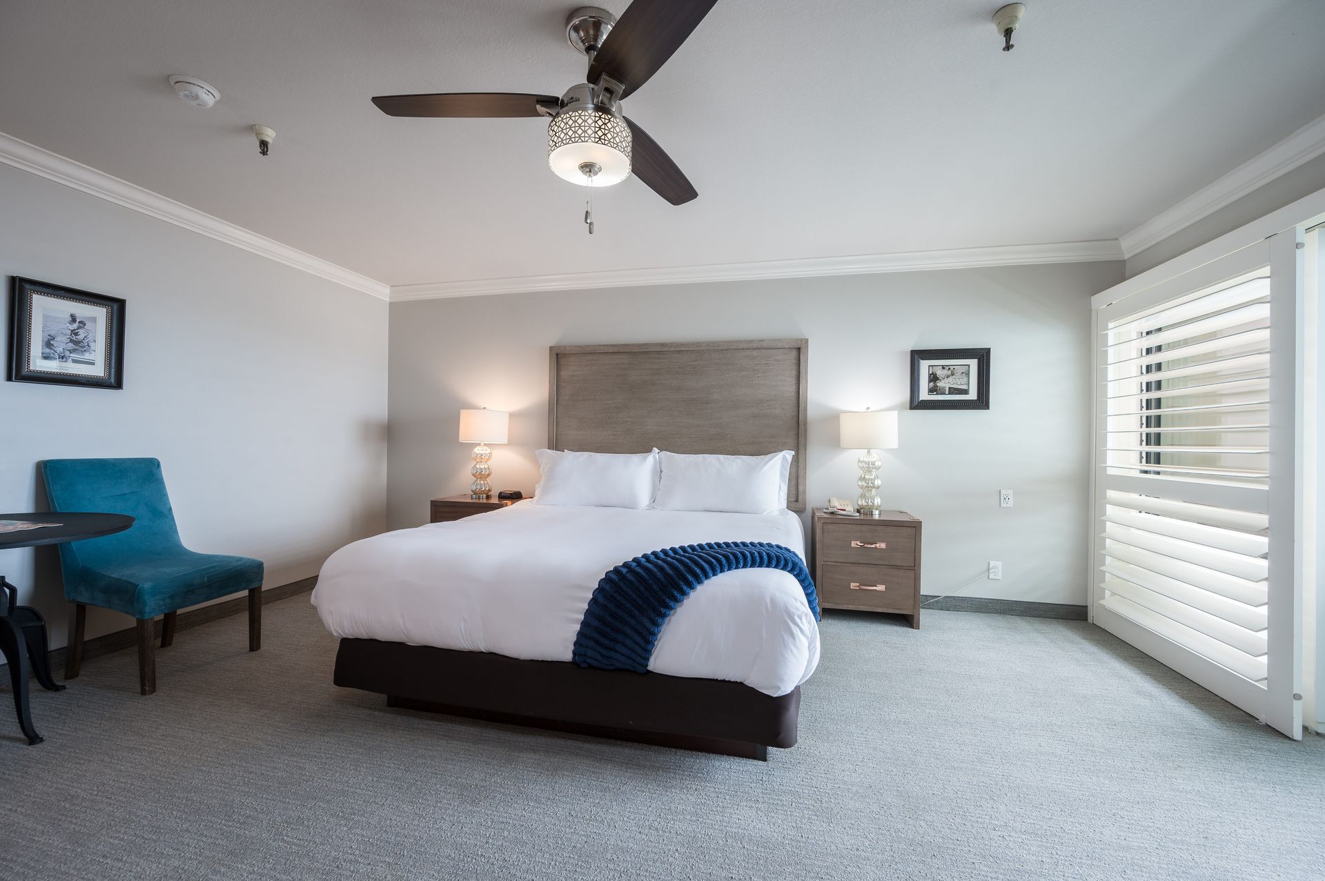 A hotel room with a king size bed and a ceiling fan.