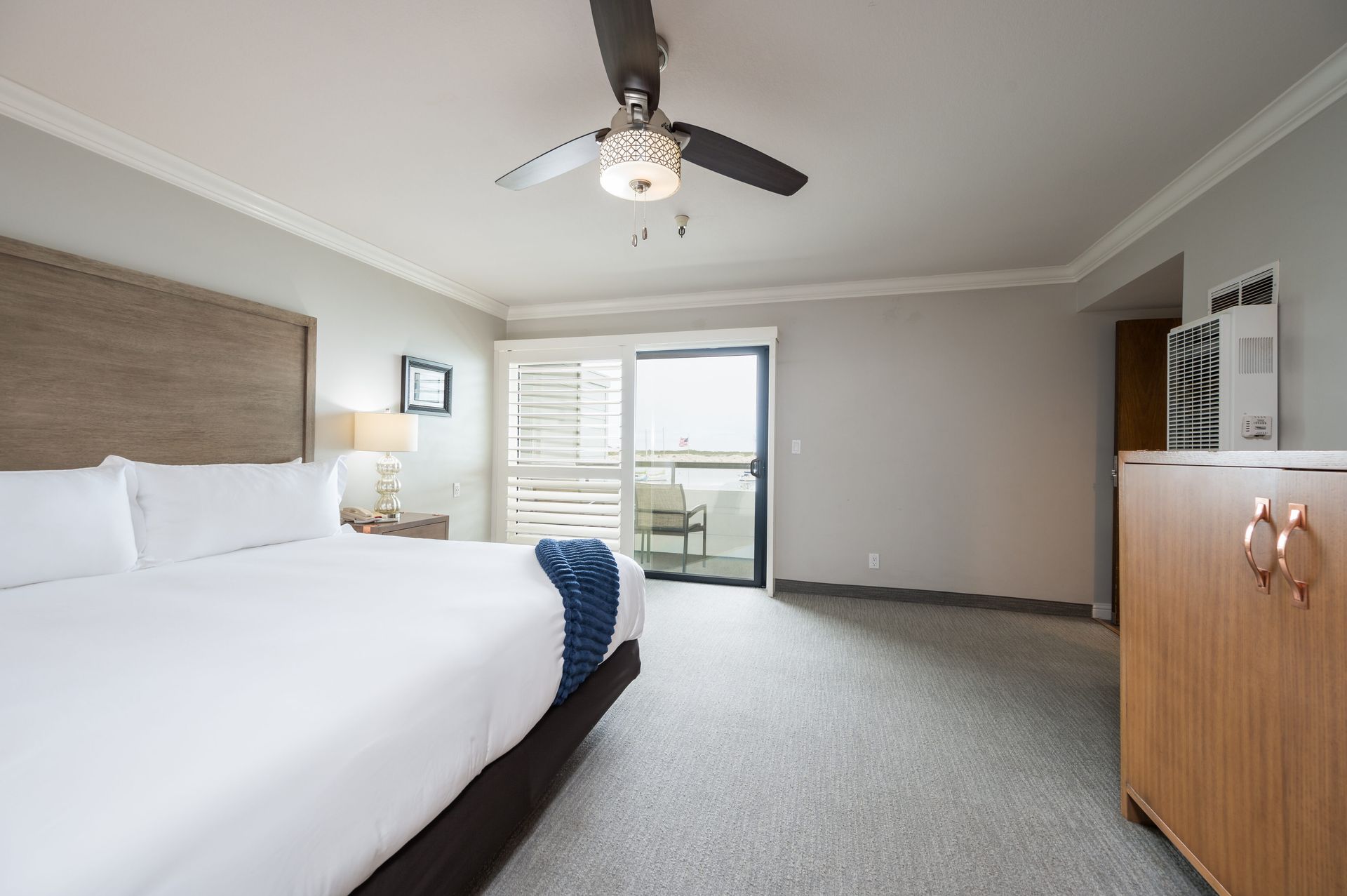 A hotel room with a king size bed and a ceiling fan