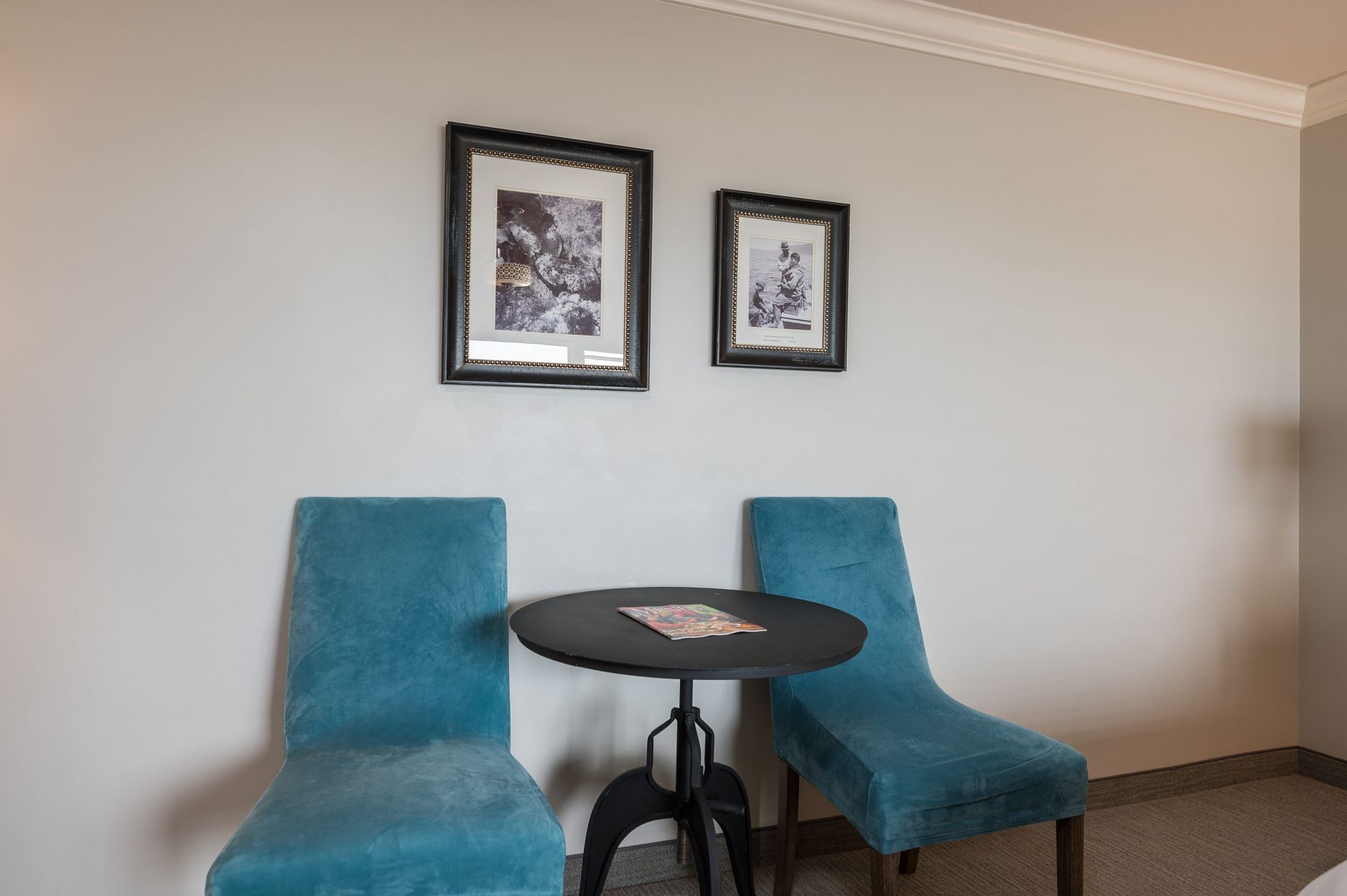 Two blue chairs are sitting next to a small table in a hotel room.