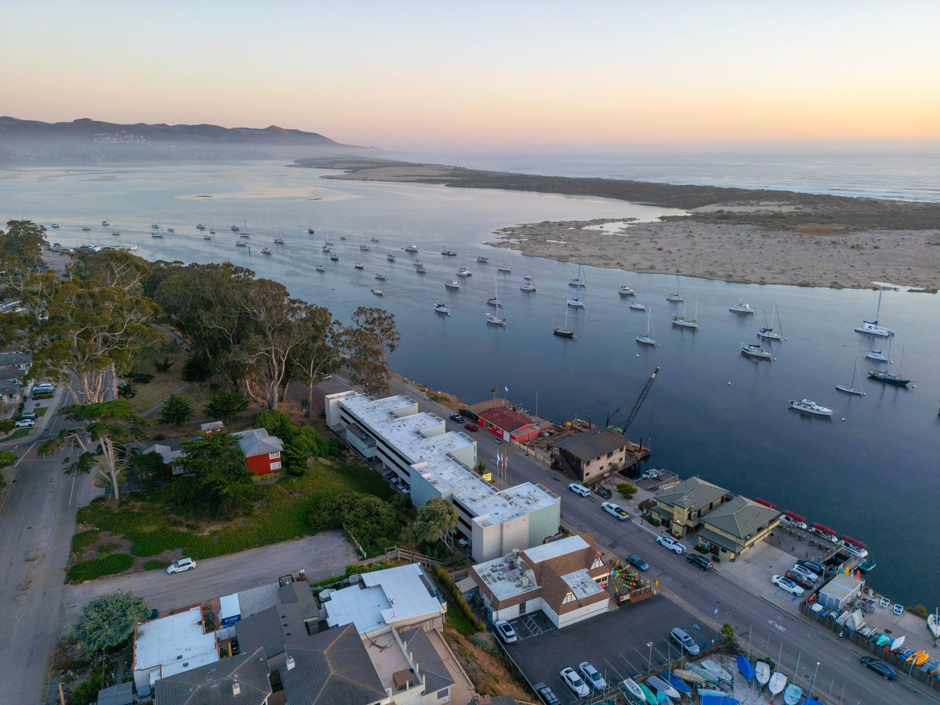 An aerial view of a harbor filled with boats and houses at sunset.