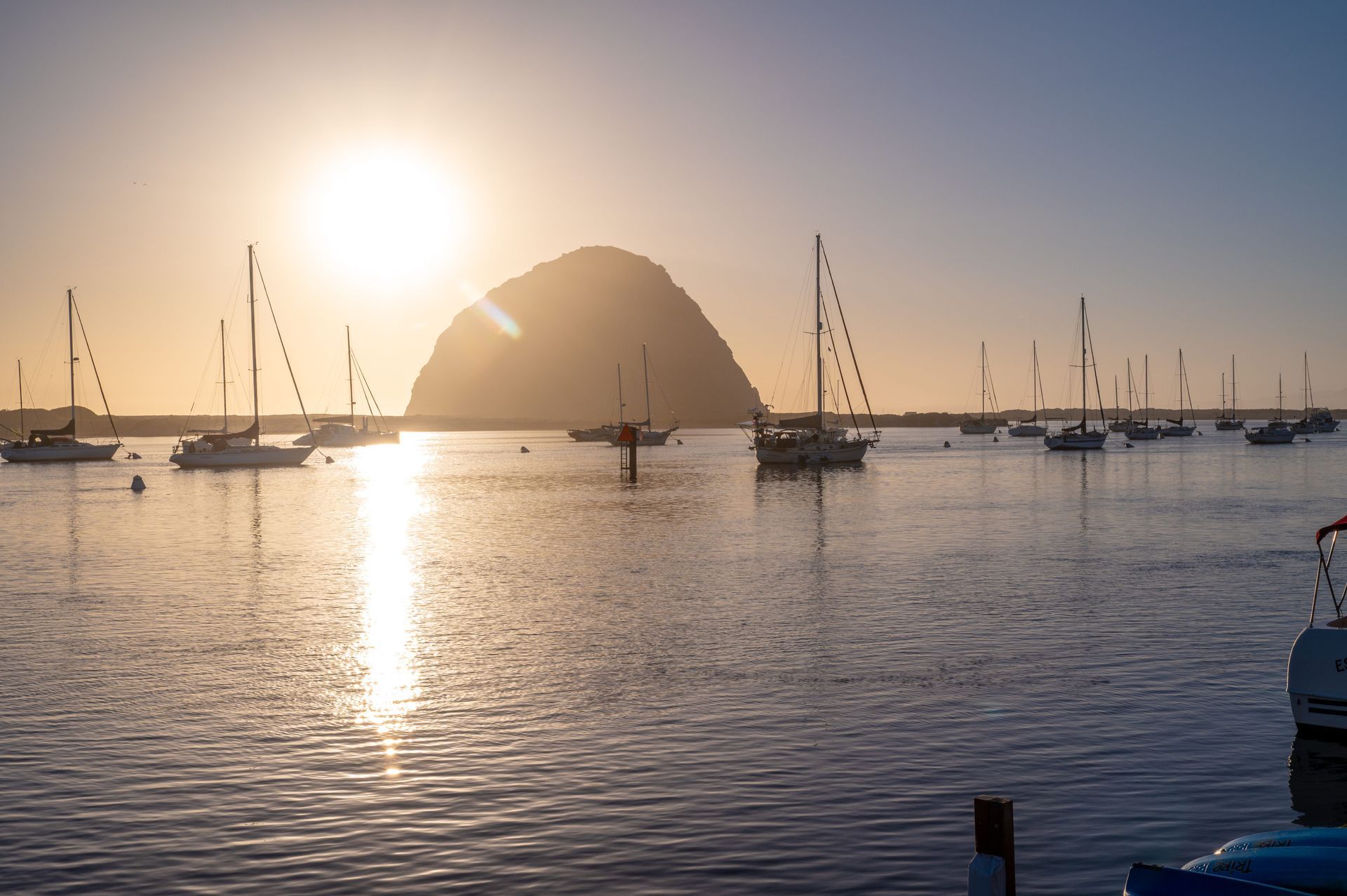 A sunset with boats in the water and a mountain in the background