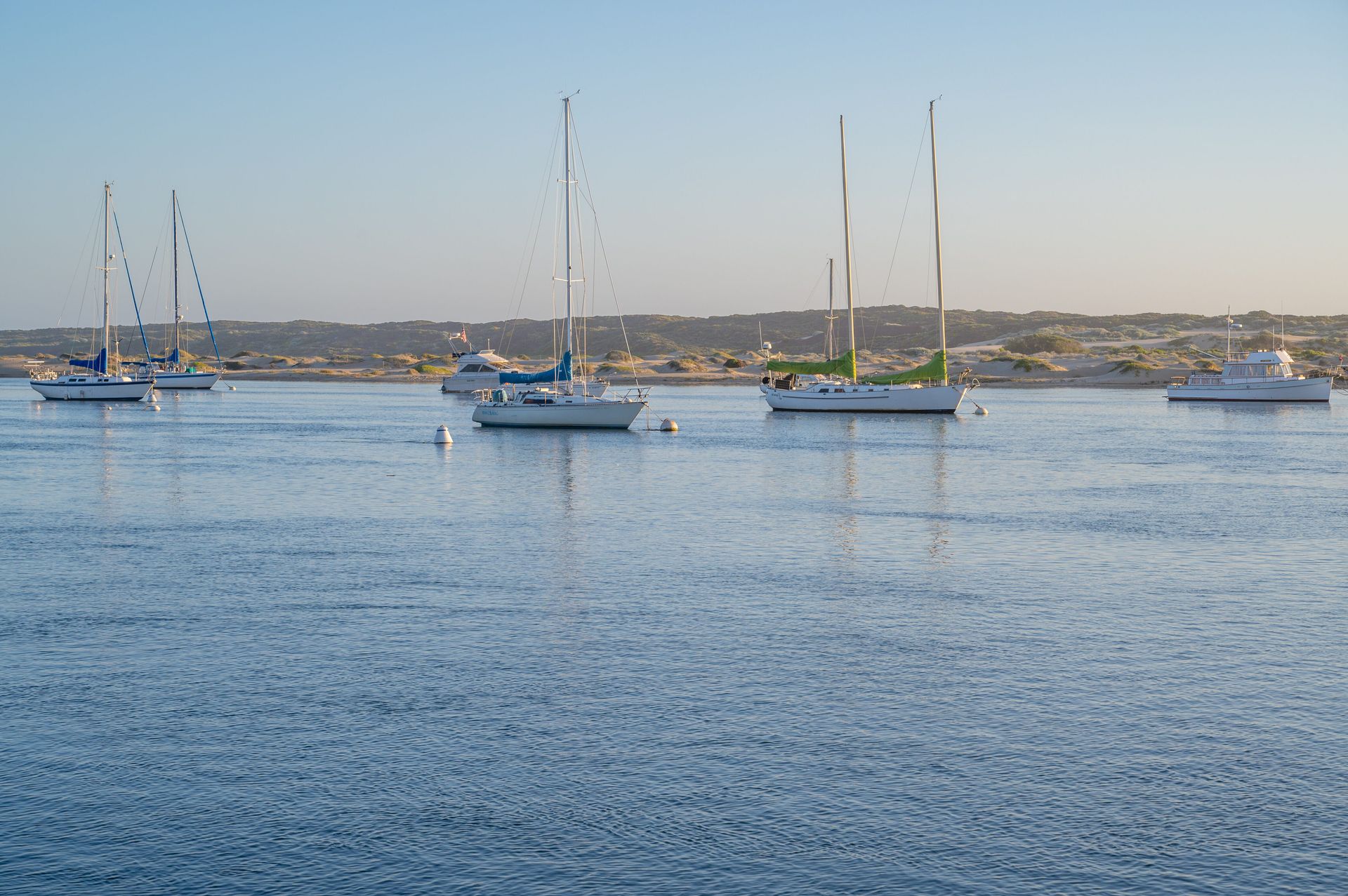 A group of sailboats are floating on top of a body of water.