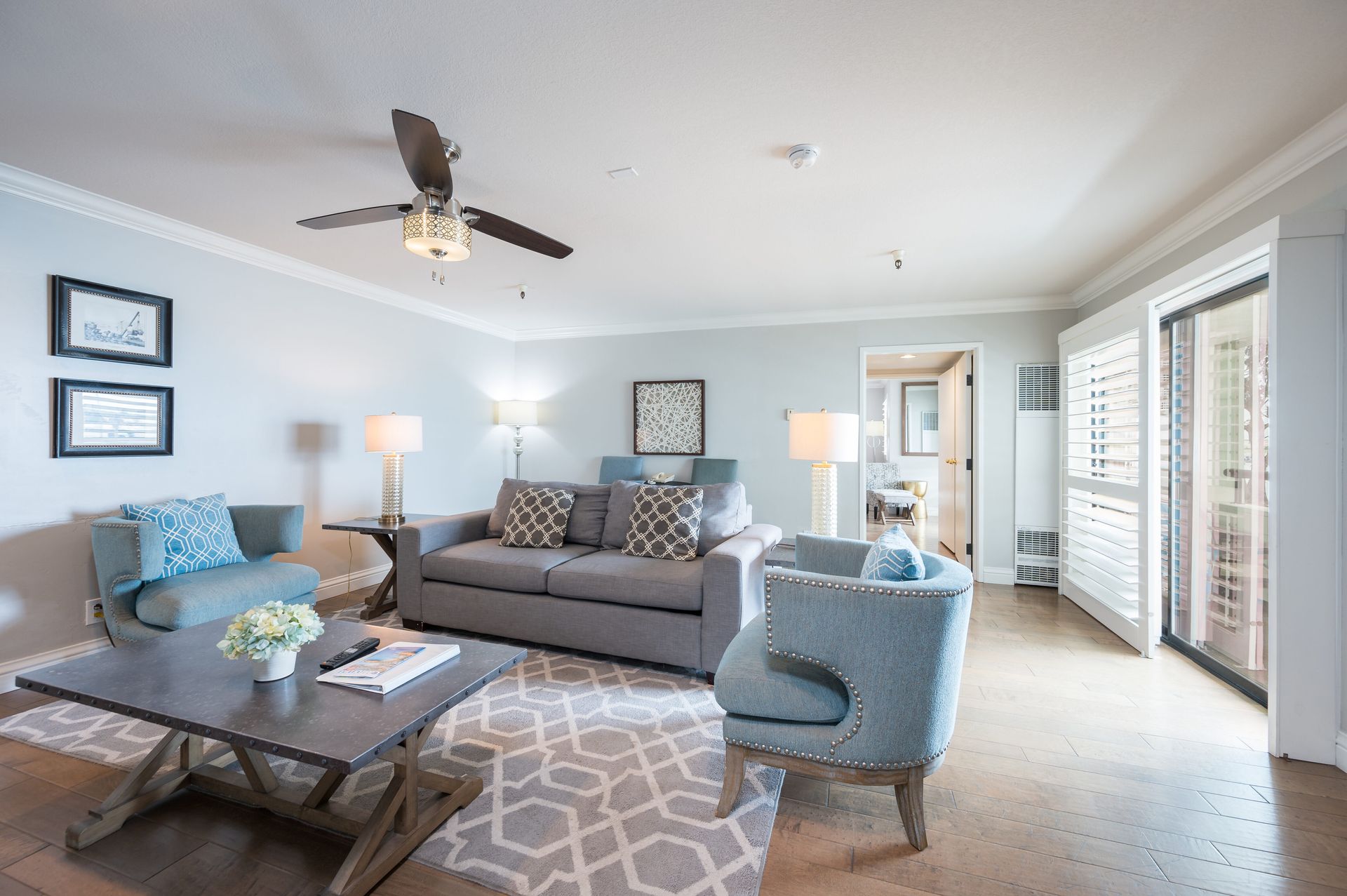 A living room with a couch , chairs , coffee table and ceiling fan.