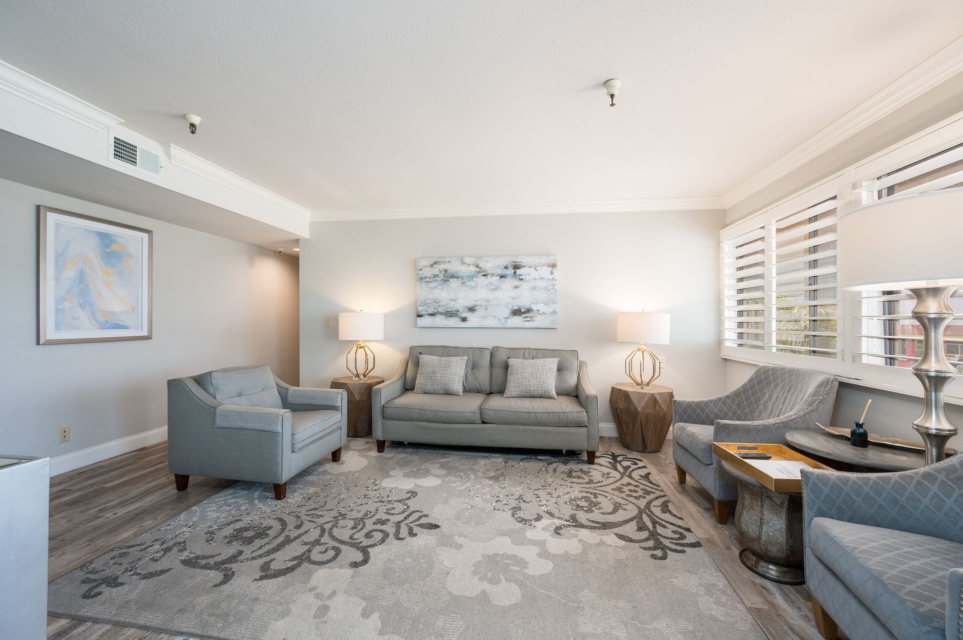 A living room with a couch , chairs , lamps and a rug.