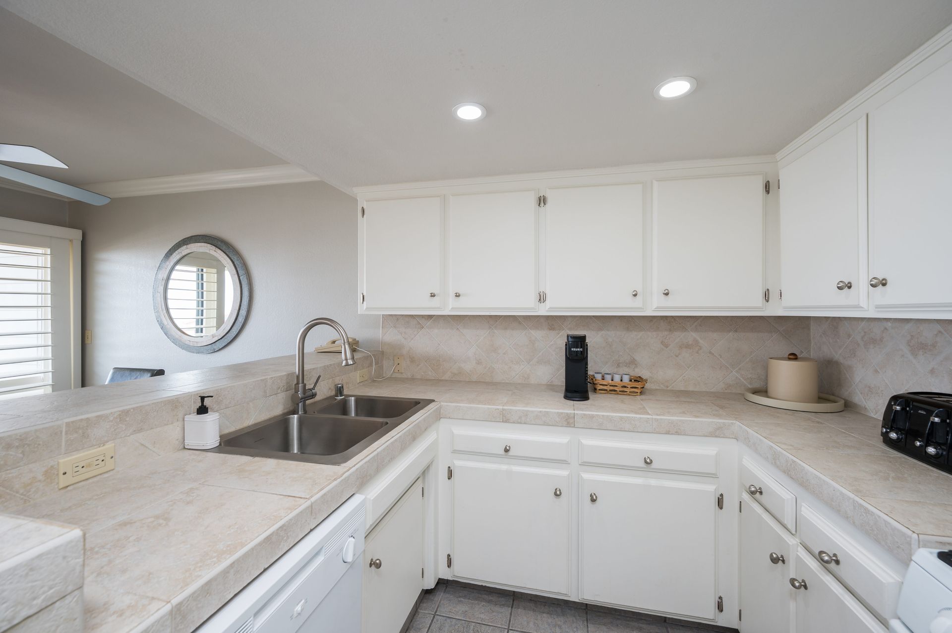 A kitchen with white cabinets and a stainless steel sink