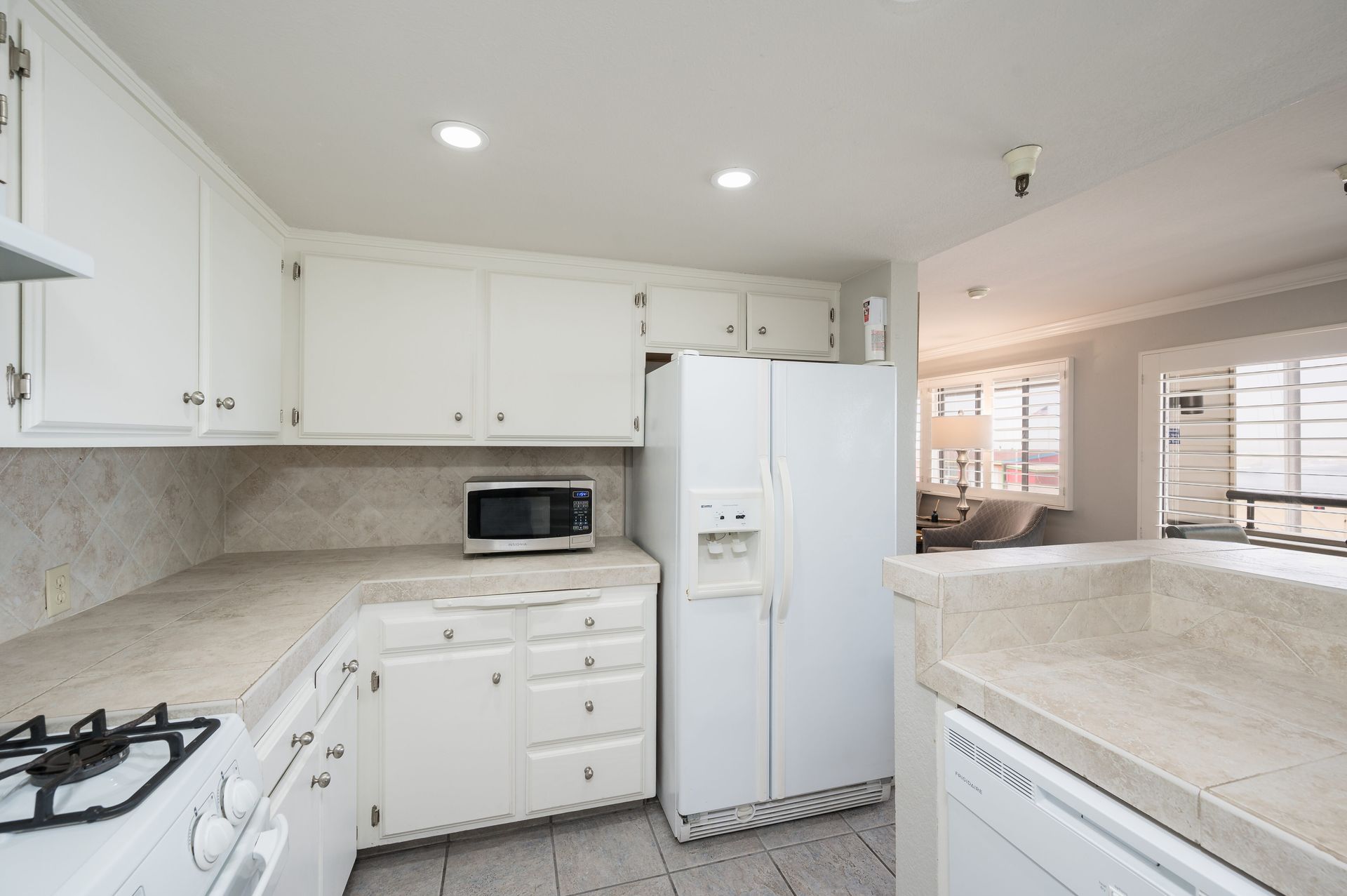 A kitchen with white cabinets and a white refrigerator