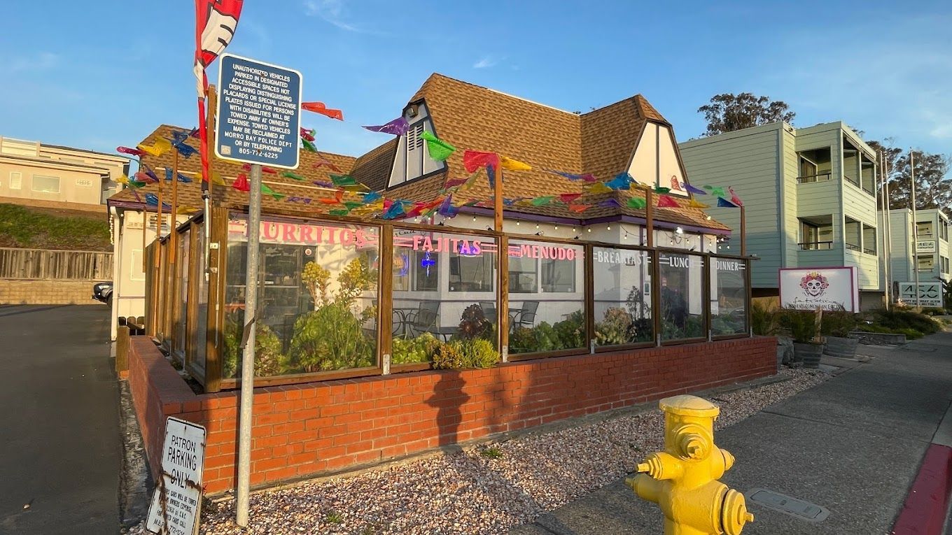 A yellow fire hydrant is in front of a restaurant.