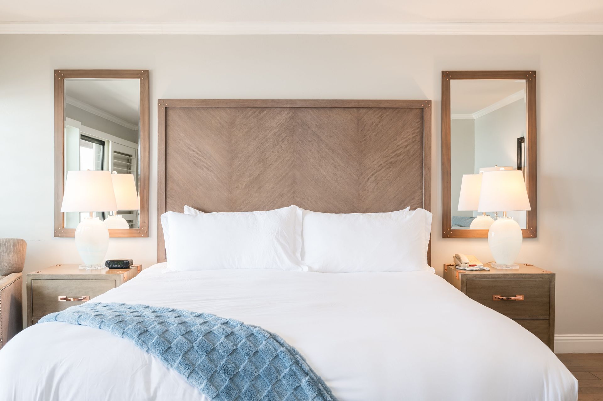 A hotel room with a large bed and two mirrors.