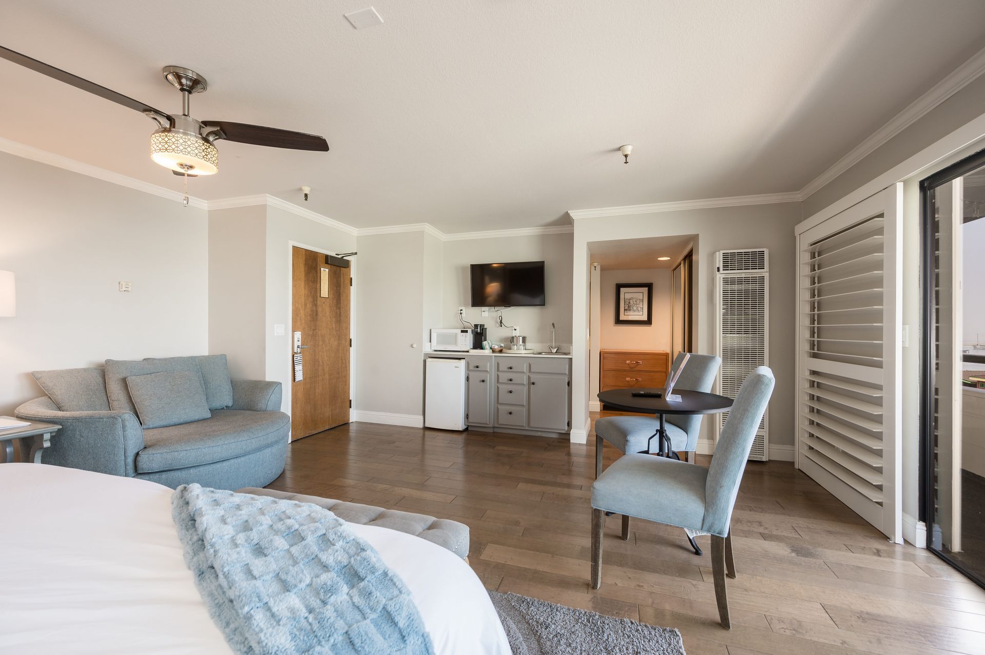 A hotel room with a bed , couch , chairs and a ceiling fan.