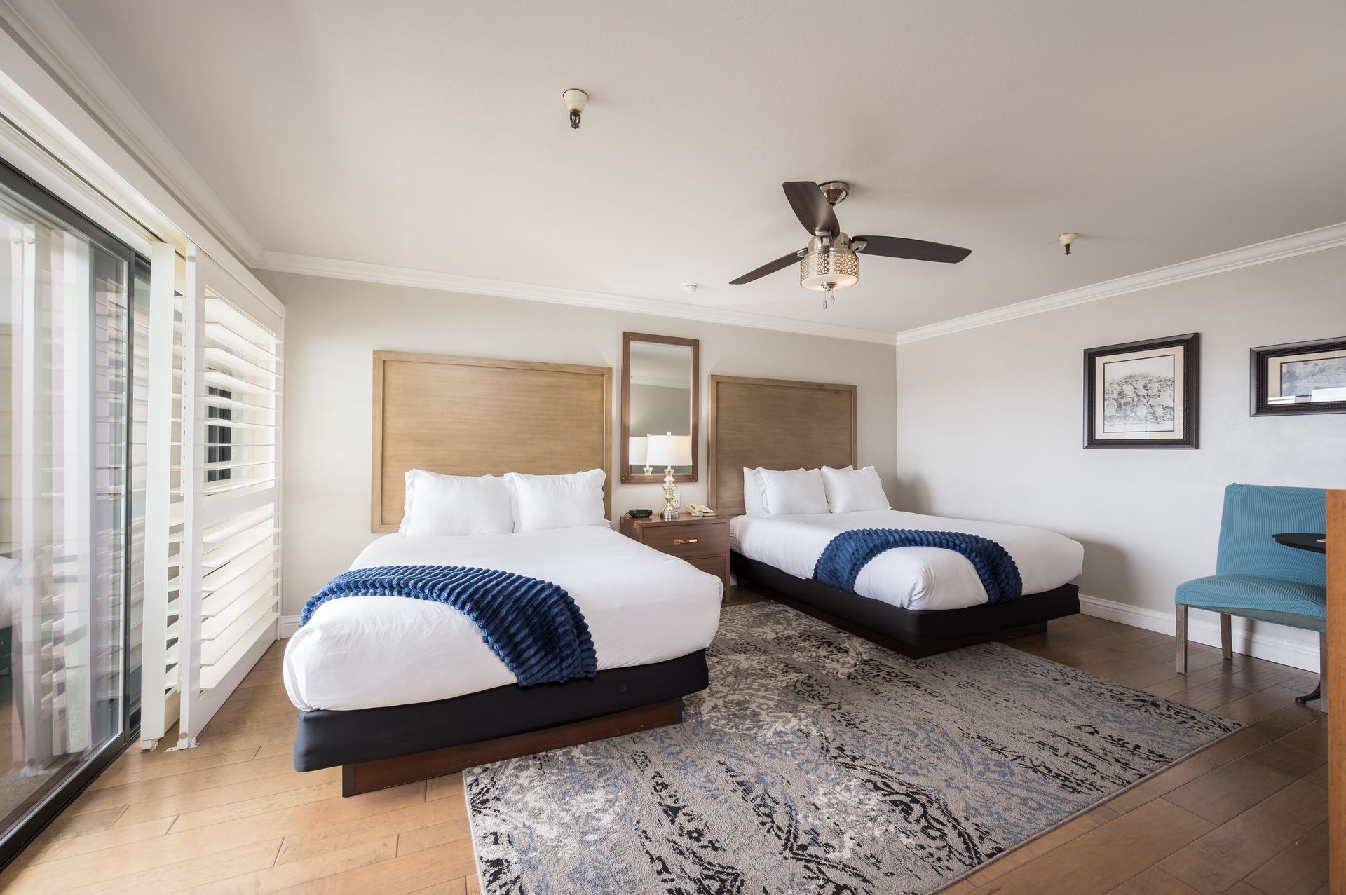 A hotel room with two beds and a ceiling fan.