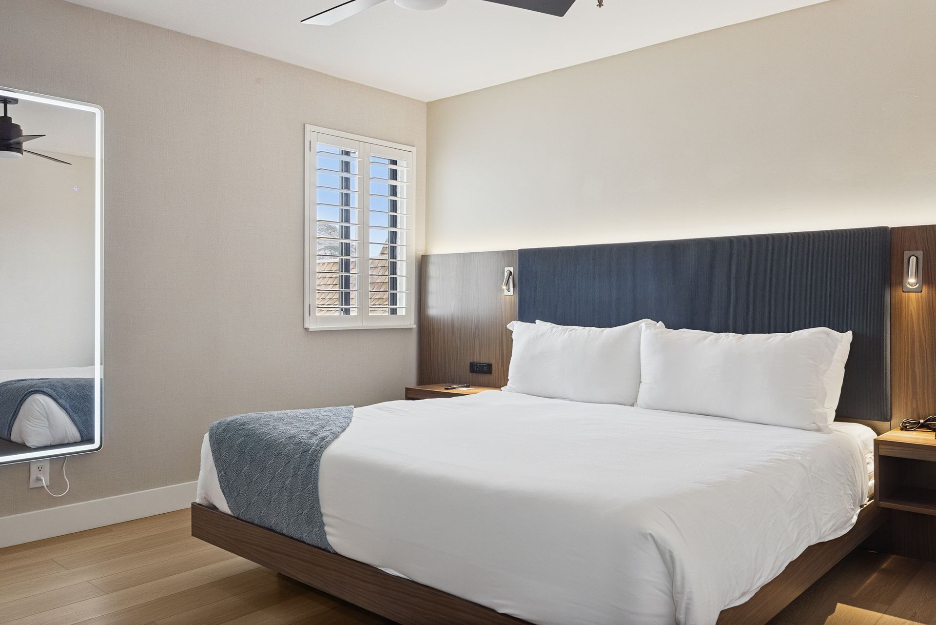 A bedroom with a king size bed , dresser , television and ceiling fan.