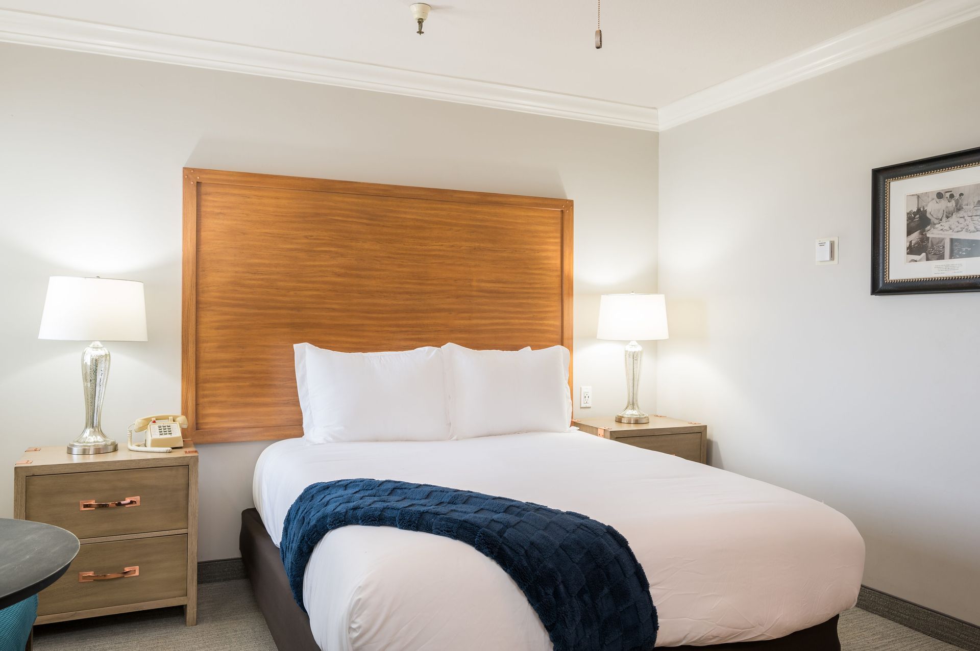 A hotel room with a bed , nightstands , lamps and a picture on the wall.