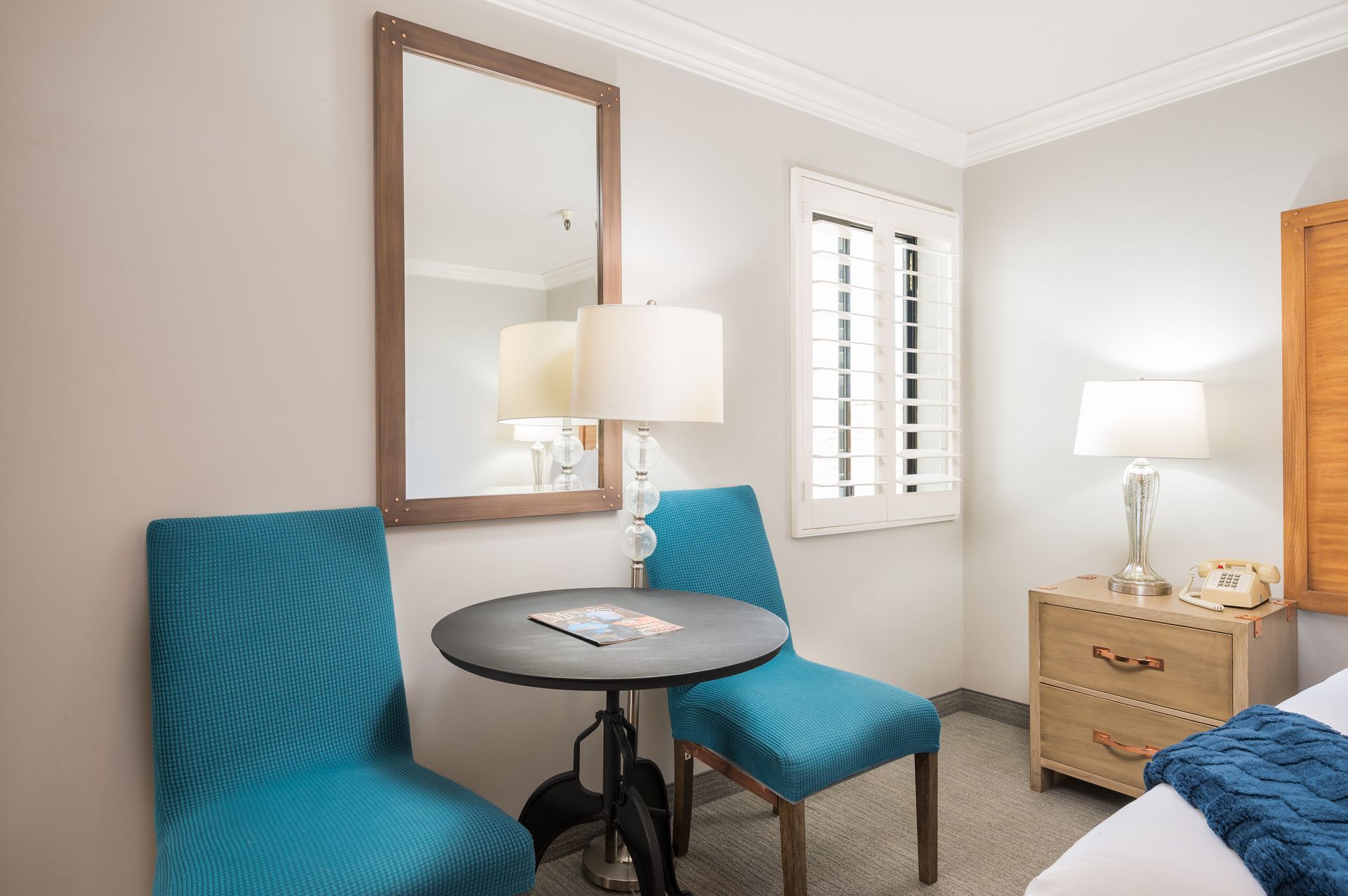 A hotel room with two chairs , a table and a mirror.