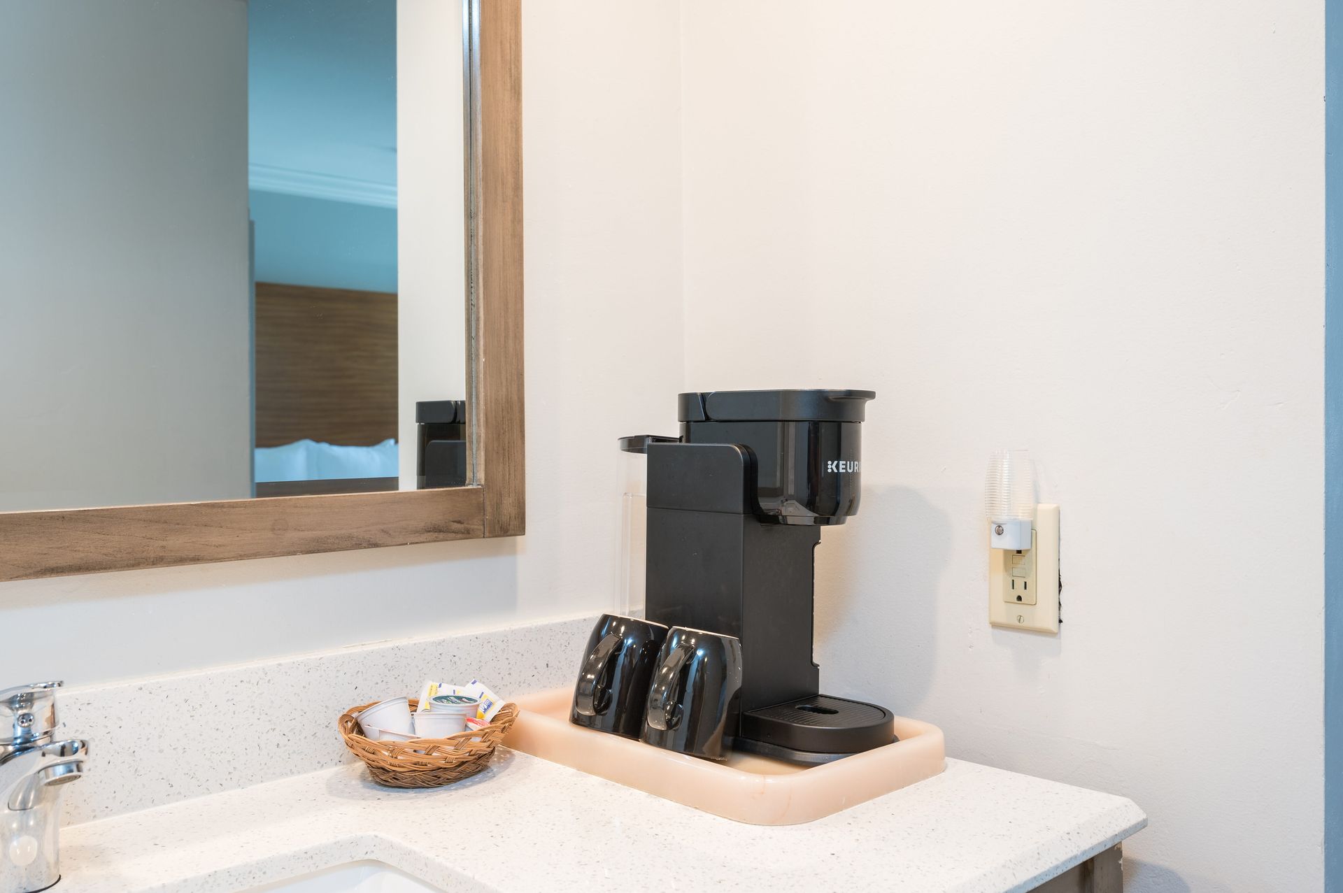 There is a coffee maker on the counter in the bathroom.