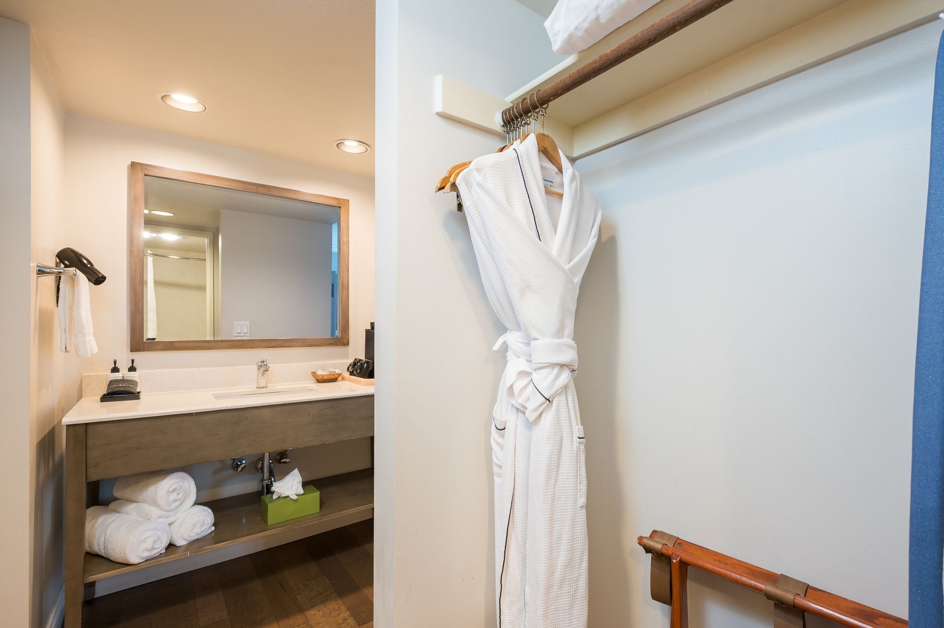 A bathroom in a hotel room with a bathrobe hanging on the wall.