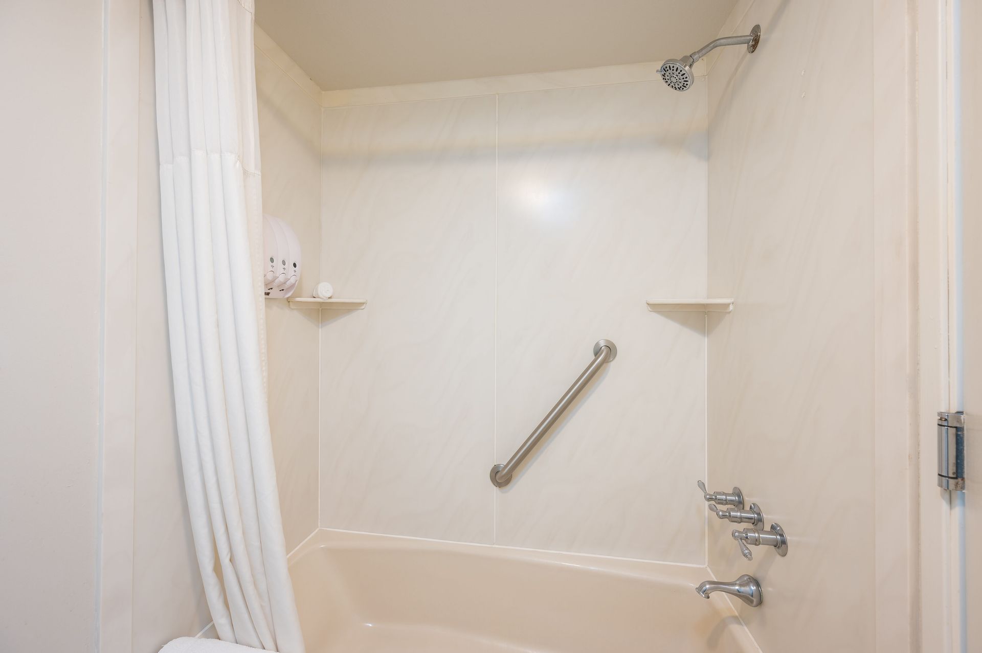 A bathroom with a tub , shower , and hand rail.