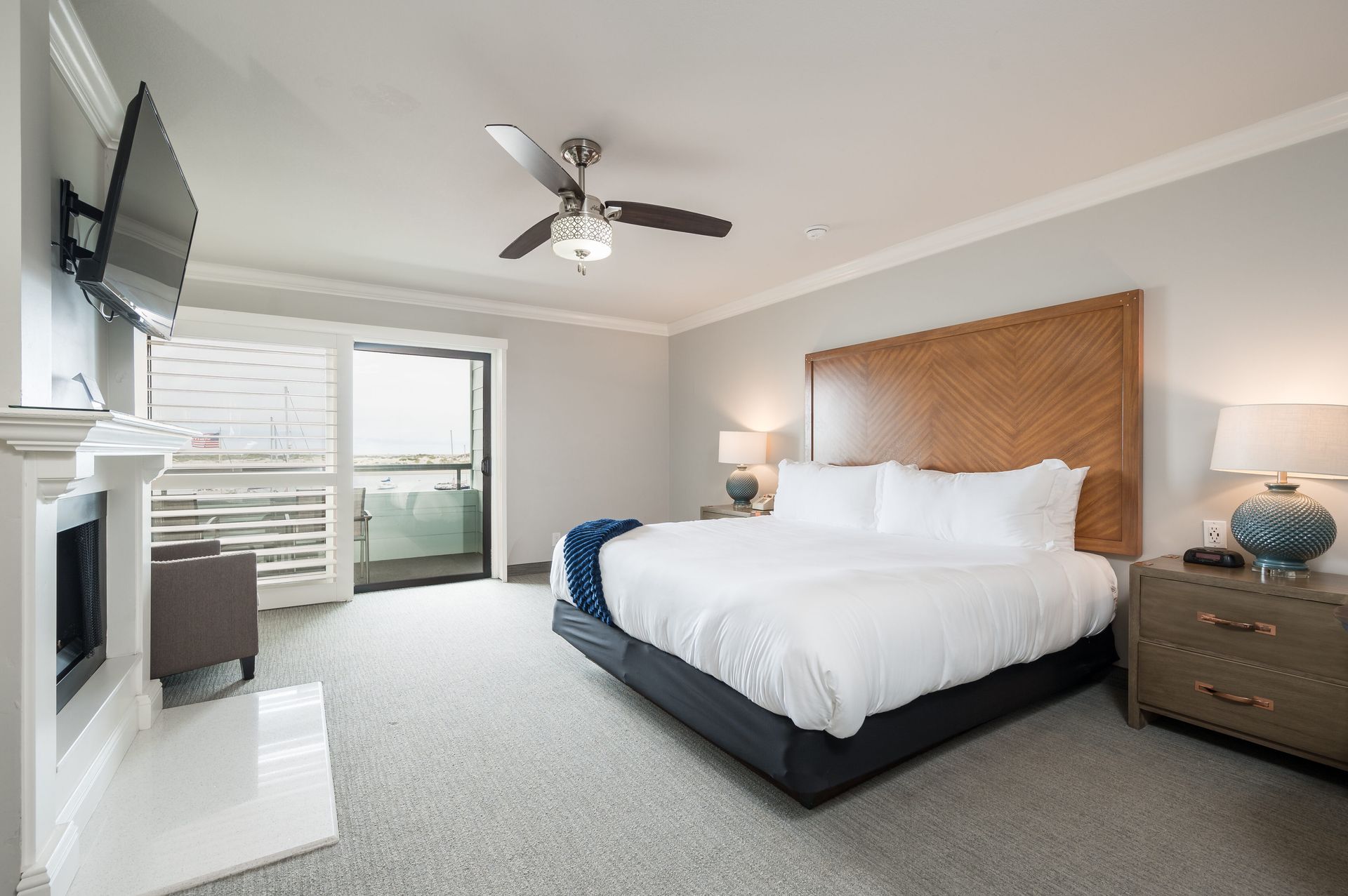 A hotel room with a king size bed , fireplace , television and ceiling fan.