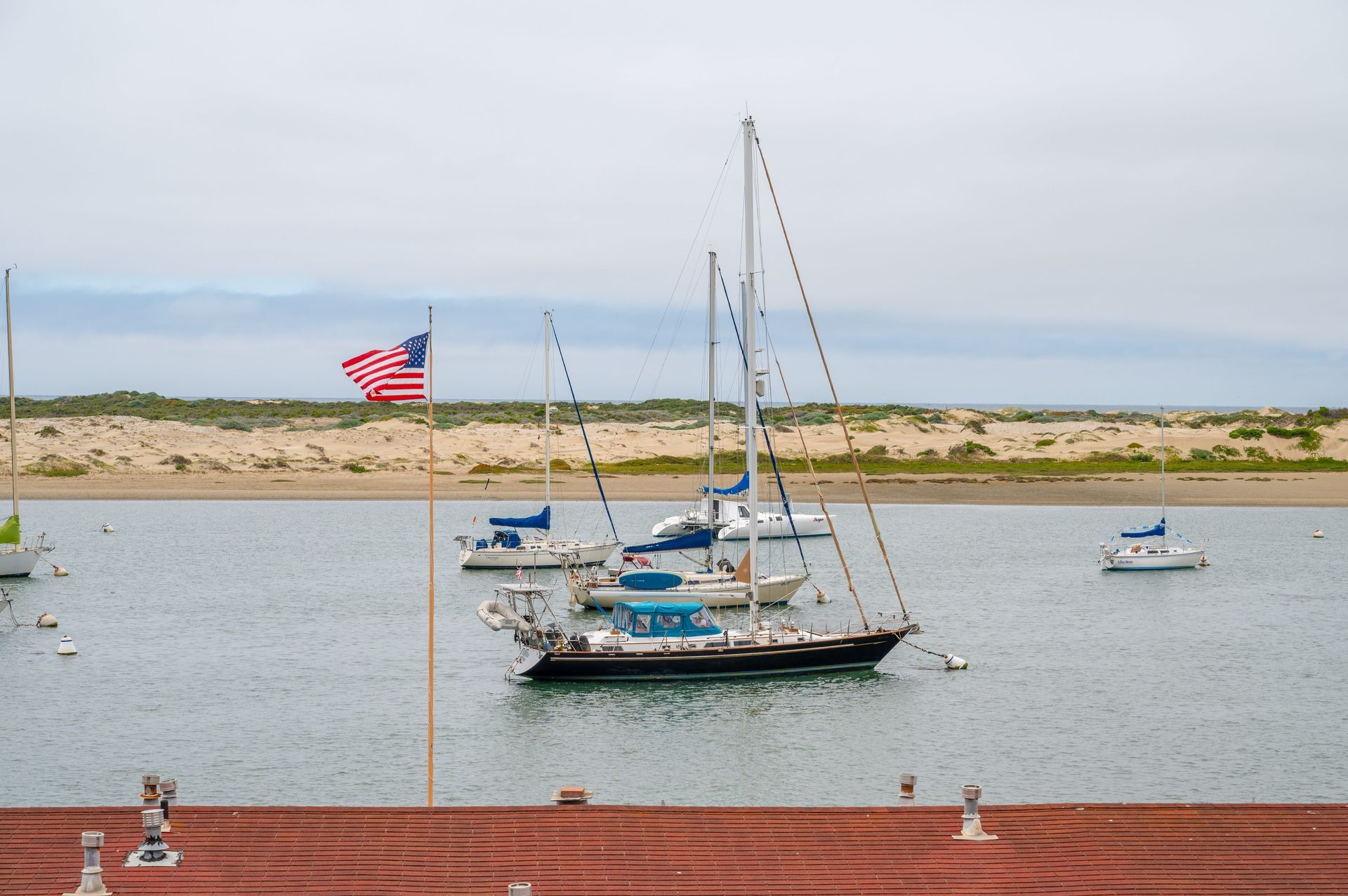 Boats are docked in a harbor with an american flag flying in the background