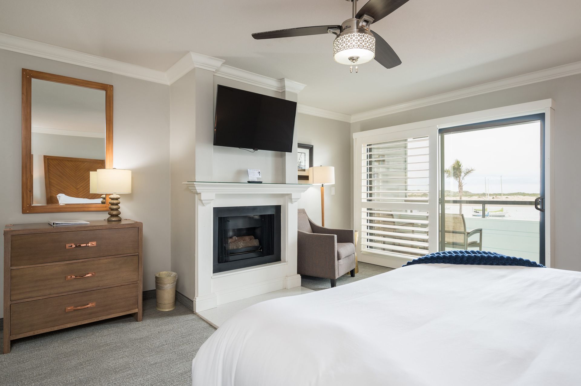 A hotel room with a bed , fireplace , television and sliding glass doors.