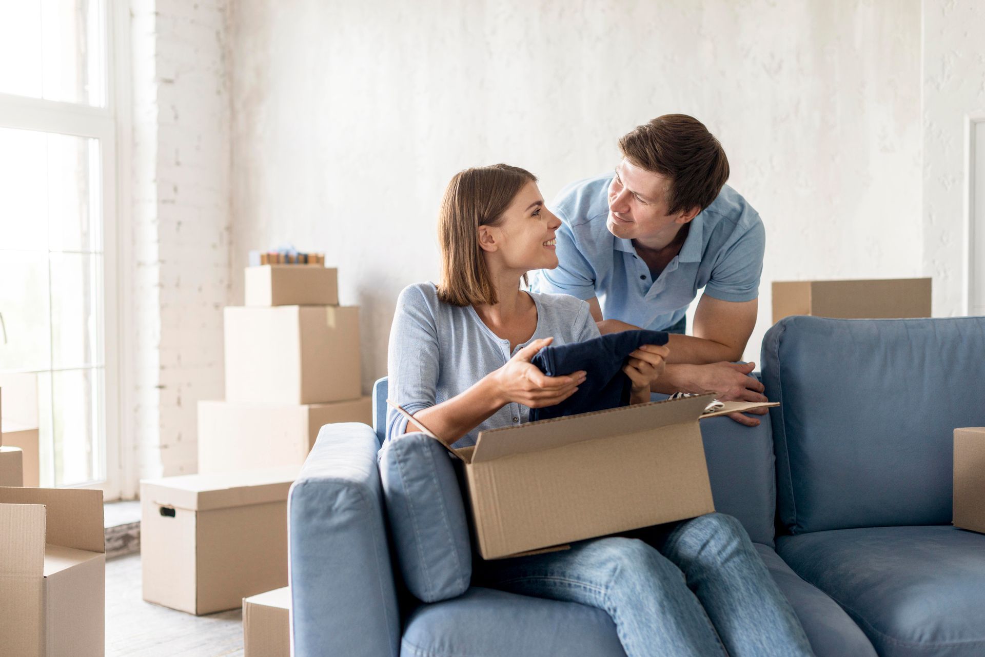A man and a woman are sitting on a couch holding boxes.
