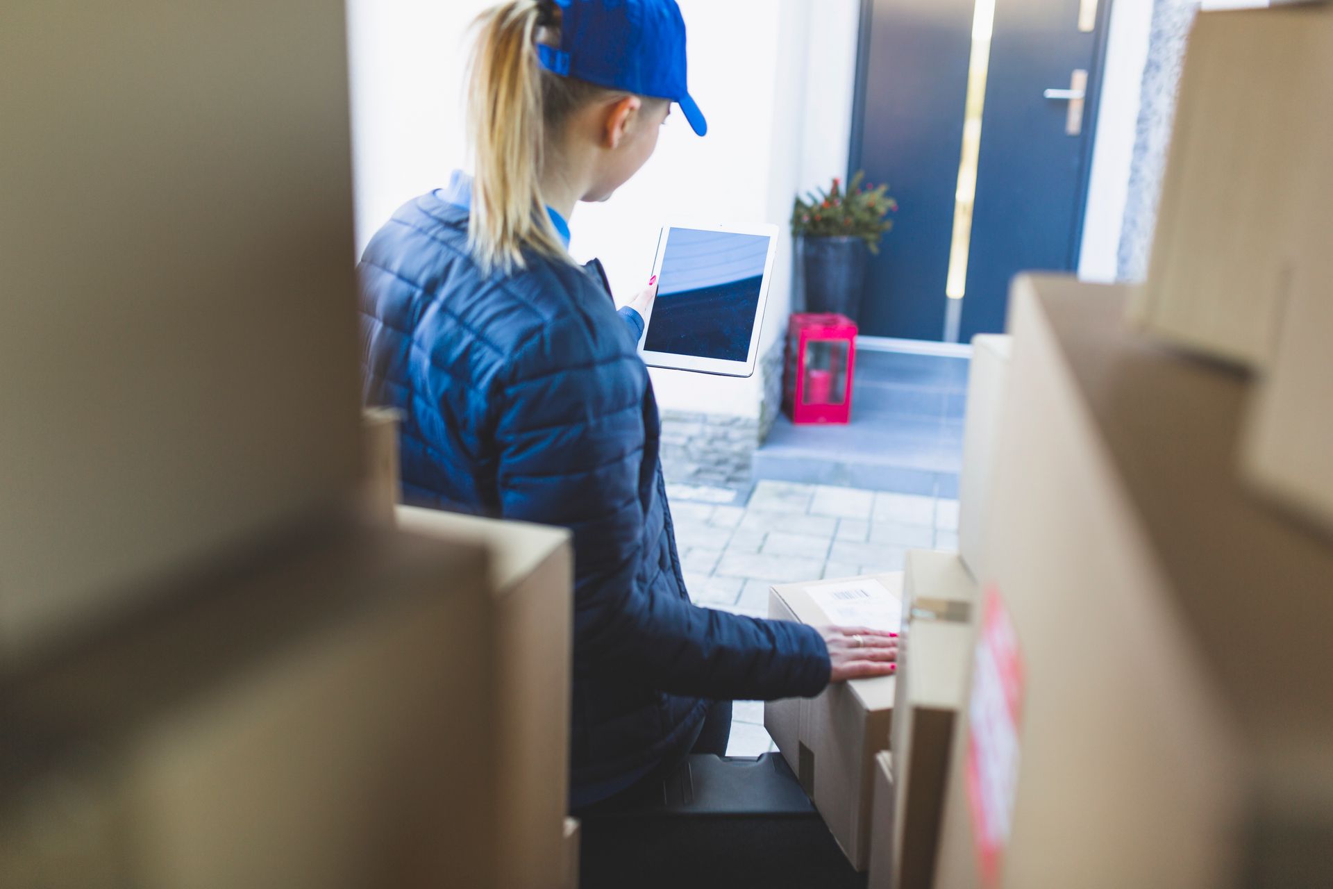 A delivery woman is sitting in front of a pile of cardboard boxes.