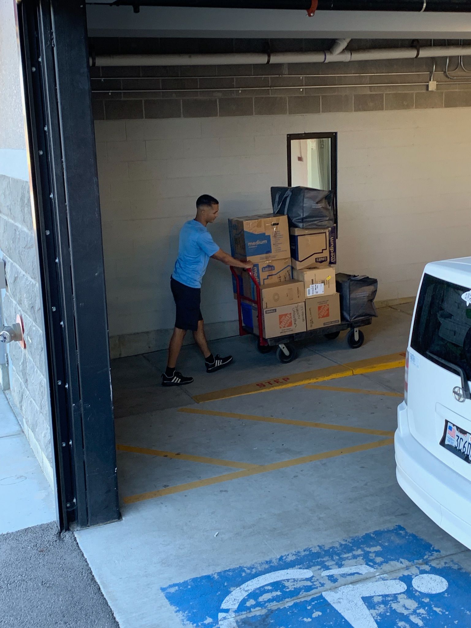 A man is pushing a cart full of boxes into a garage.