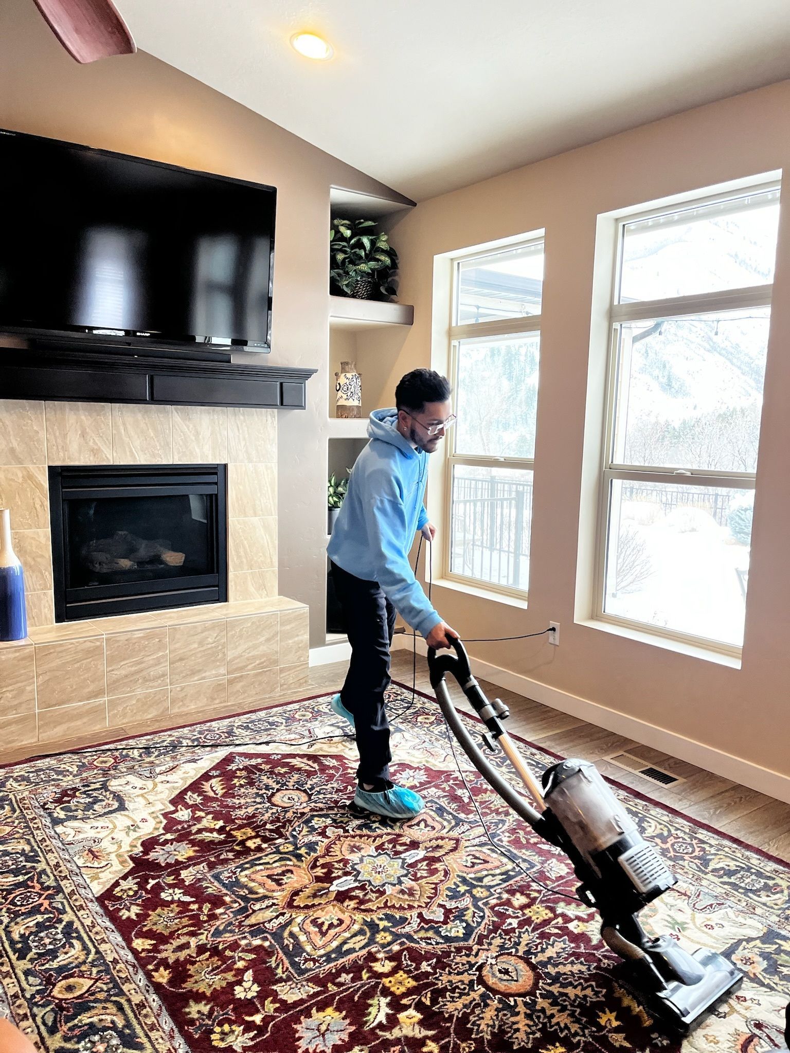 A man is vacuuming a rug in a living room.
