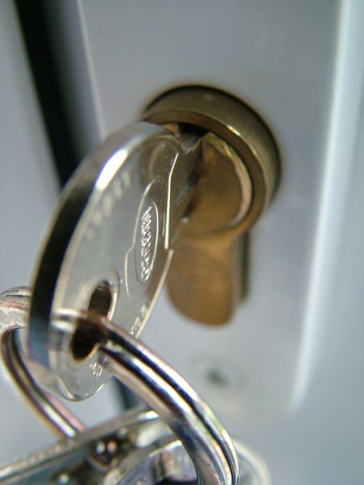 A bunch of keys and a lock on a wooden table.