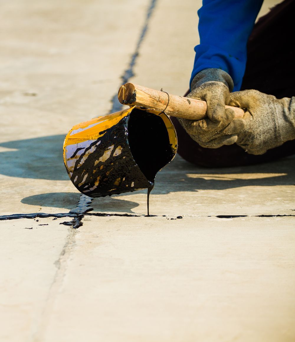 A person is pouring paint from a bucket onto a concrete surface