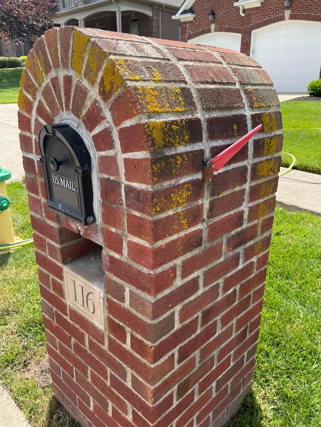 A brick mailbox with a red mailbox sticking out of it.