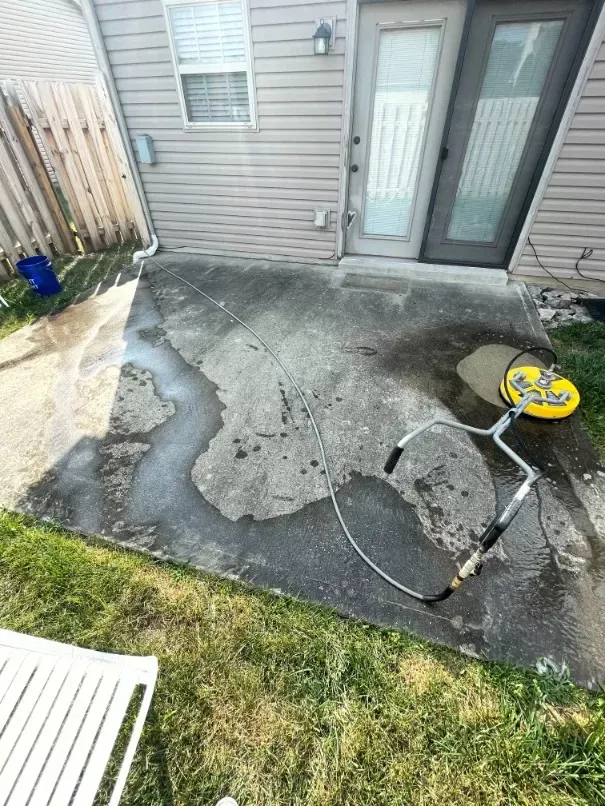 A concrete patio is being cleaned in front of a house.
