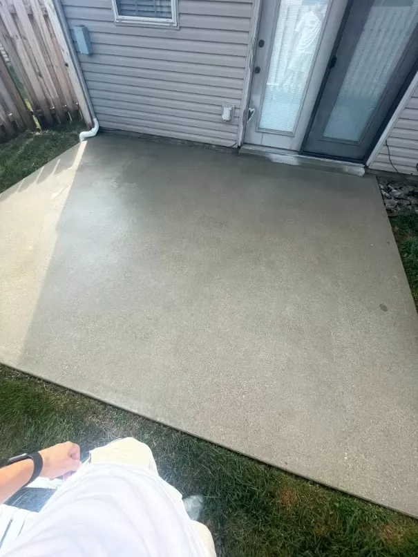 A person is standing on a concrete patio in front of a house.