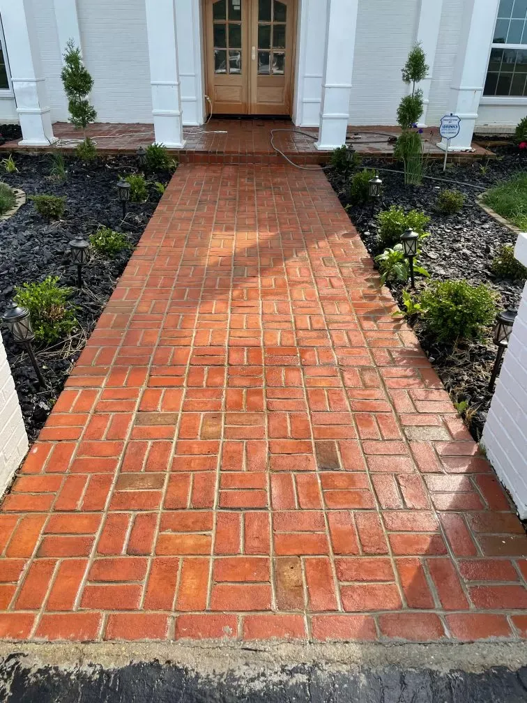 A red brick walkway leading to the front door of a house.