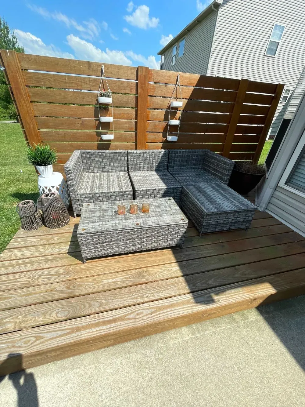 A wooden deck with a couch and ottoman on it.