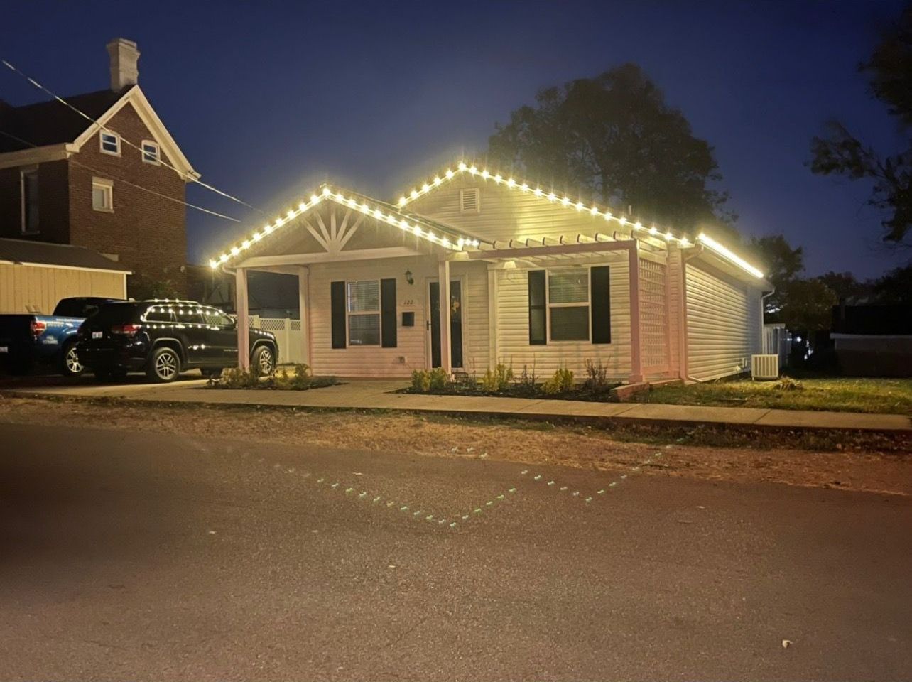 A house with christmas lights on the roof is lit up at night.