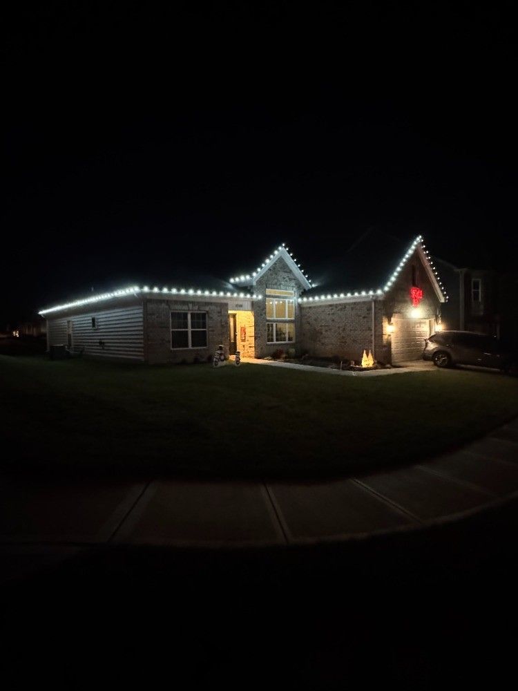 A house with christmas lights on it is lit up at night.