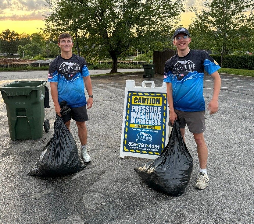 Two young men in matching blue shirts holding black trash bags