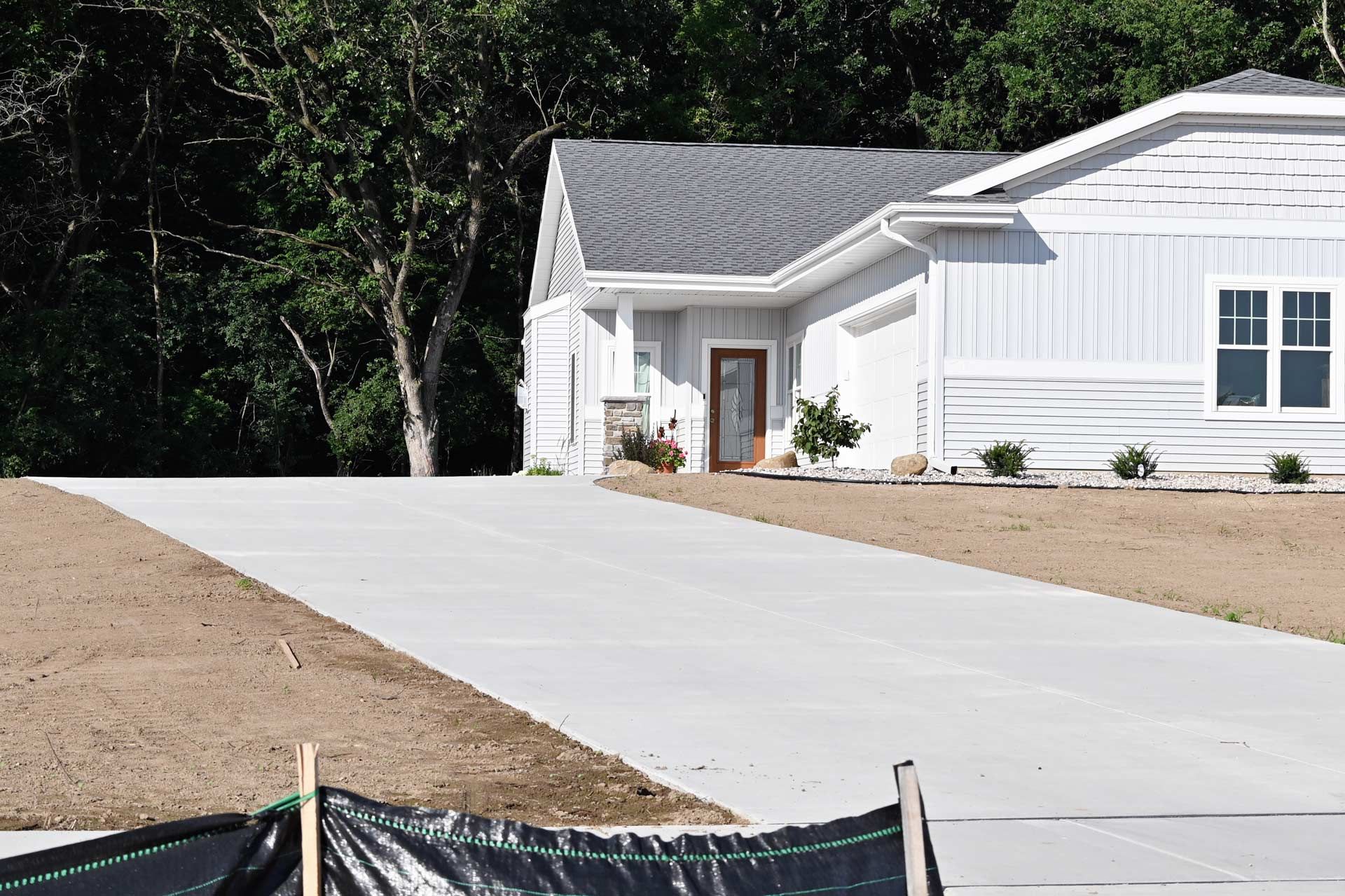 A newly poured concrete driveway leading to a modern residential home exterior. A newly poured concrete driveway leading to a modern residential home exterior.