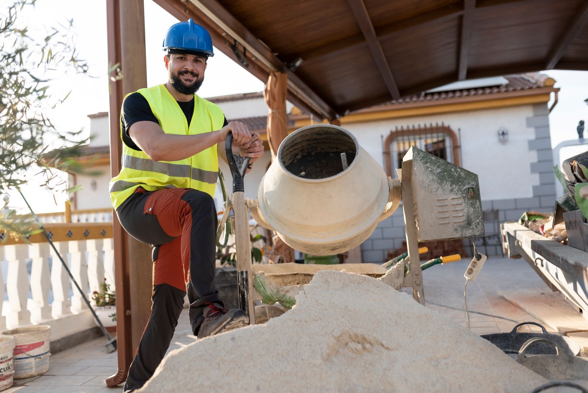 A worker in safety gear operating a cement mixer at a sunny construction site