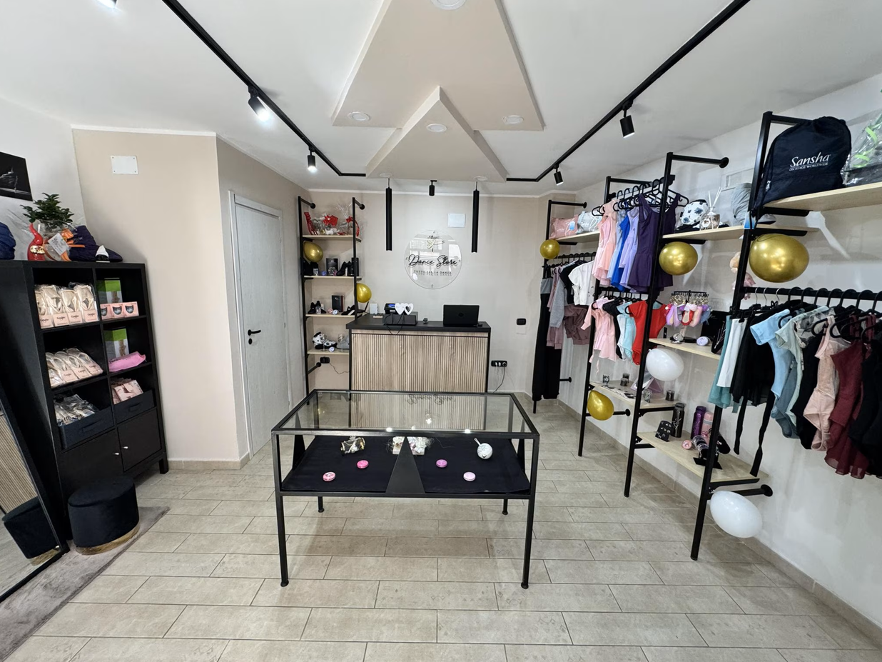 Interno di un negozio di abbigliamento con espositori, vetrina e merce. Combinazione di colori beige e nero.