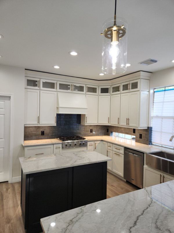 A kitchen with white cabinets , granite counter tops , stainless steel appliances and a large island.