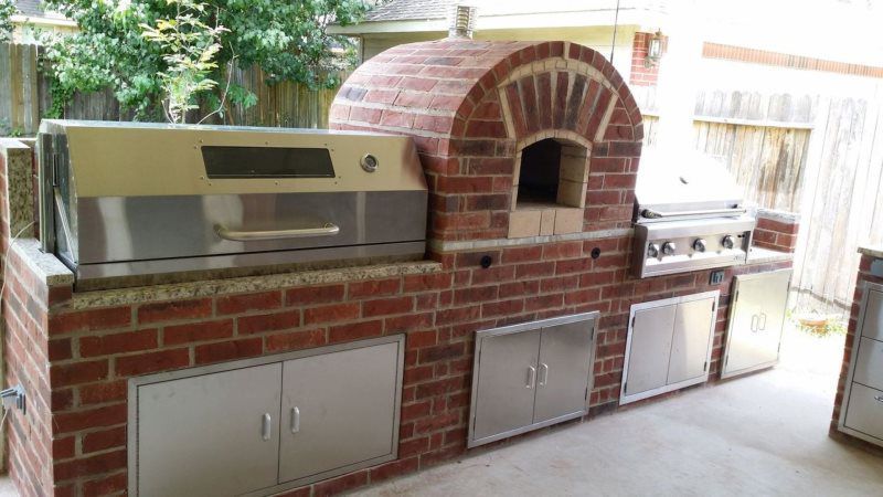 An outdoor kitchen with a brick oven and a grill