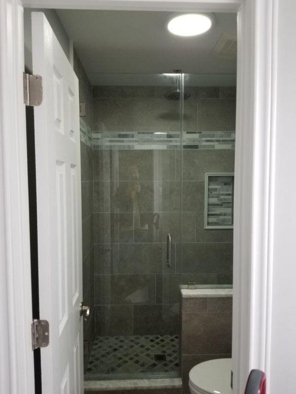 A bathroom with a glass shower door and a toilet.