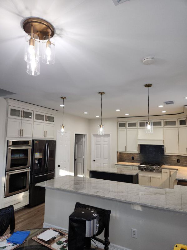A kitchen with white cabinets , stainless steel appliances , and a large island.