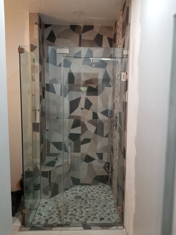 A bathroom with a walk in shower and a tiled wall.