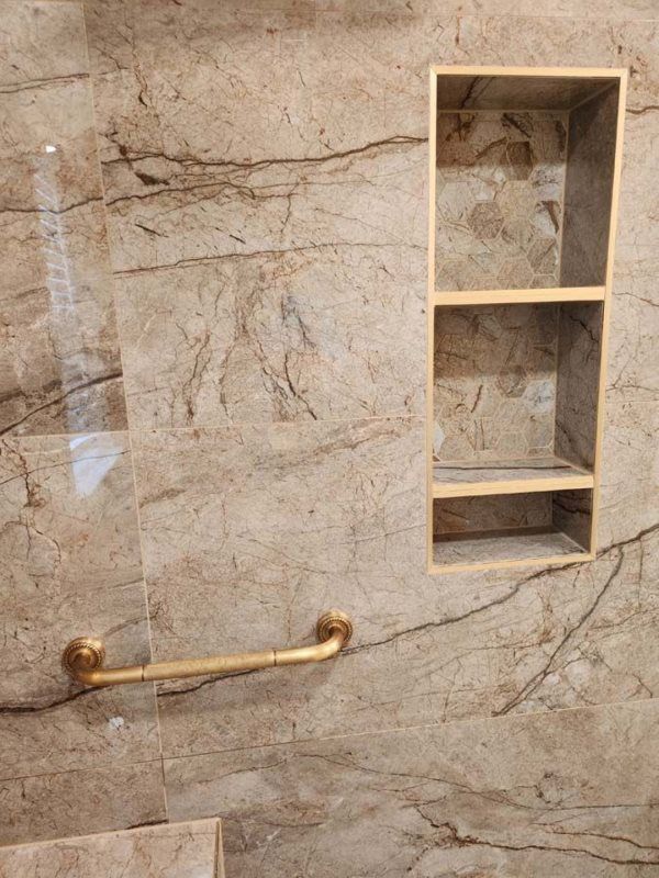 A bathroom with a marble wall and a shelf.